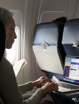A person using a MacBook Air while sitting on an airplane, to demonstrate the device's long battery life